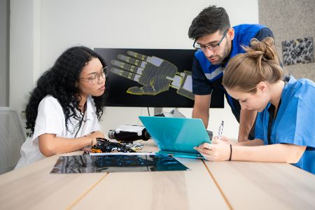 Vor dem digitalen Modell einer Hand prüden Ärzte eine Prothese