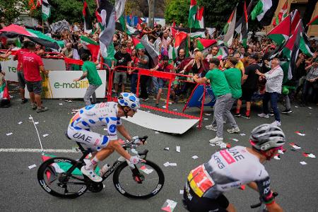 Menschen protestieren an der Strecke mit palästinensischen Fahnen gegen die Teilnahme des Radrennstalls Israel-Premier Tech an der Vuelta á España