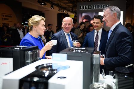 Wirtschaftssenatorin Franziska Giffey lässt sich gemeinsam mit dem Regierenden Bürgermeister Kai Wegner einen Espresso am Stand von Jura Elektrogeräte schmecken.