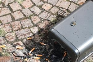 Der angebrannte Mülleimer mit den Zigarettenresten