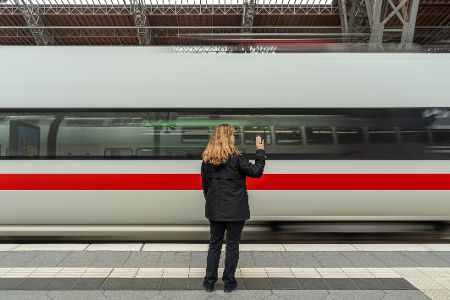 Frau steht vor abfahrendem Schnellzug und winkt Frau steht vor abfahrendem Schnellzug und winkt