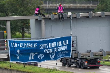 Klimaaktivisten protestieren auf der A9 in der Nähe der Allianz Arena mit einem Plakat gegen die IAA.