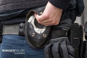 Das Symbolbild zeigt einen Bundespolizisten mit dem Griff an dessen Handfesseln