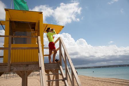  Ein Rettungsschwimmer benutzt ein Fernglas, während er am Strand von Palma auf Mallorca patrouilliert. 
