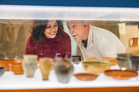 Ältere Frau und älterer Mann sehen sich Ausstellungsstücke in einer Vitrine an