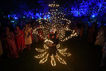 Ein Mann hält in einem mit Öllampen geschmückten Kostüm in der fünften Nacht von Navratri, dem Fest der neun Nächte, das Aarti-Ritual ab.