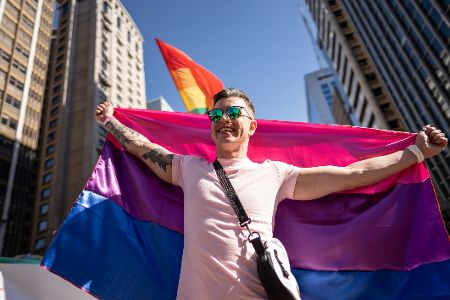 Mann mit Bisexualität-Flagge auf einer Pride Parade