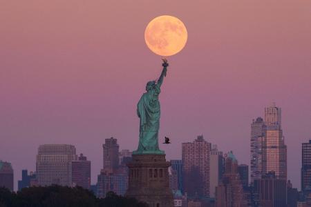 Der Supermond geht hinter der Freiheitsstatue in New York auf.