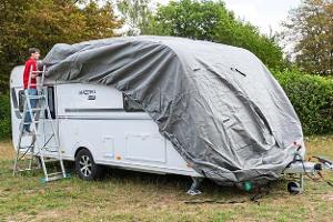 Die Schutzhülle wird von vorne nach hinten über den Caravan gezogen.