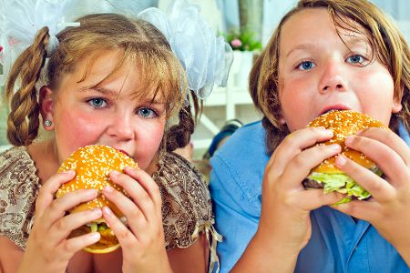 Ein Junge und ein Mädchen beißen herzhaft in einen Burger