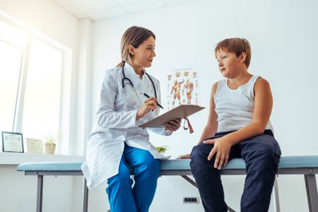 Ärztin spricht in einer Praxis mit einem leicht übergewichtigem Jungen