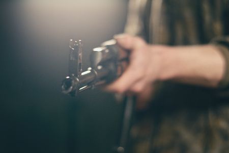Person in Flecktarn hält Maschinengewehr in Richtung Kamera