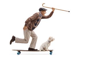 Alter Mann mit Gehstock in der Hand und ein Hund fahren auf einem Longboard