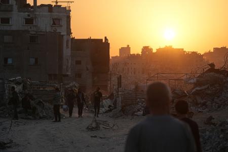 Palästinenser gehen in Gaza-Stadt an Häusern vorbei, die durch die israelische Luft- und Bodenoffensive zerstört wurden.
