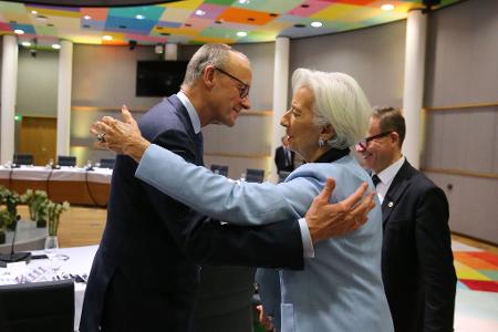 Bundeskanzler Friedrich Merz (l) umarmt Christine Lagarde, Präsidentin der Europäischen Zentralbank, während eines Essens im Rahmen des Euro-Gipfels.