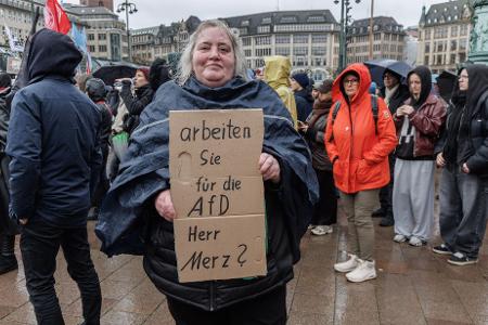 Eine Demonstrantin in Hamburg stellt auf einem Pappschild eine Frage an Bundeskanzler Friedrich Merz (CDU).  Eine Demonstrantin in Hamburg stellt auf einem Pappschild eine Frage an Bundeskanzler Friedrich Merz (CDU).