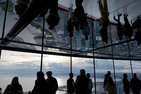 Menschen schauen vom CN Tower in Toronto auf das Rogers Centre und den Ontariosee.