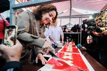Amsterdams Bürgermeisterin Femke Halsema schneidet die lange Torte an. 