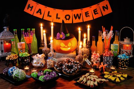 Tisch dekoriert mit einem Halloween-Schild und verschiedenen gruseligen Speisen und Drinks in passender Optik Tisch dekoriert mit einem Halloween-Schild und verschiedenen gruseligen Speisen und Drinks in passender Optik