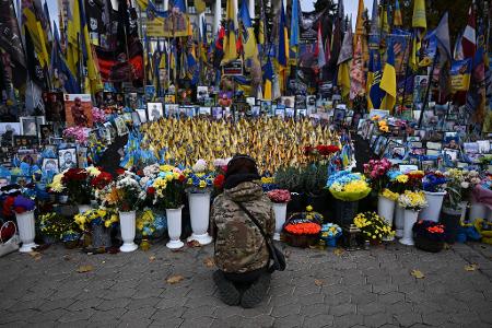Eine junge Frau kniet am Unabhängigkeitsplatz Maidan in Kiew. Hier wird den Gefallenen des Krieges gedacht.