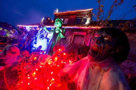 Gruselige Figuren stehen in Mettmann vor einem beleuchteten Halloween-Haus.