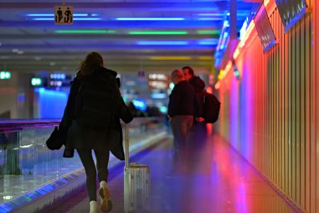 Eine Frau rennt mit ihrem Koffer neben einem Rollsteig am Flughafen. Heute ist der letzte Schultag vor den Herbstferien in Bayern.