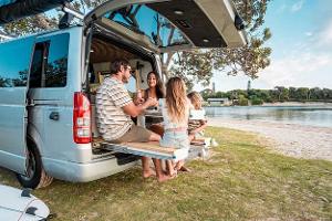 Young Family Enjoying Outdoor Meal by Scenic Sea