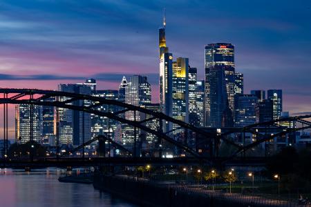Die Lichter der Bankenskyline von Frankfurt leuchten in der Abendstimmung.