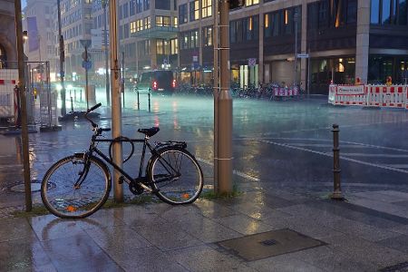 Fahrrad steht angelehnt an einer Straße in der Stadt bei Starkregen