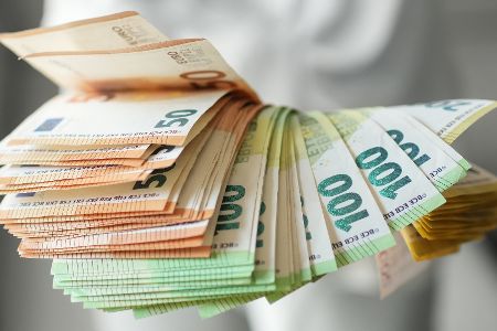 Mensch hat Bündel mit Geldscheinen in der Hand