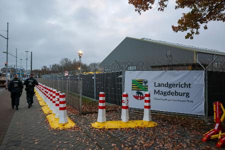Polizisten laufen vor dem temporären Gerichtsgebäude des Landgerichtes Magdeburg Streife.