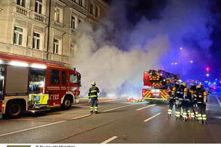Einsatzkräfte vor dem Haus. Im Hintergrund eine starke Rauchentwicklung..