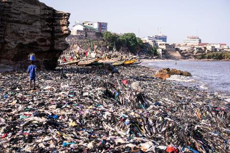 Ein Sandstrand, dessen Sand gar nicht mehr zu sehen ist: Massen an Klamotten vermüllen diesen Küstenabschnitt von Accra. 