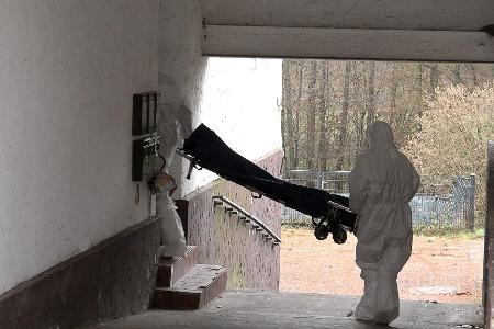 Beamte der Spurensicherung bringen eine Trage in ein Wohnhaus. 