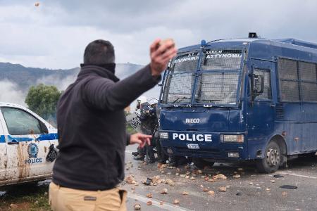 Ein Landwirt wirft bei Bauernprotesten in Griechenland Steine auf die Polizei. 