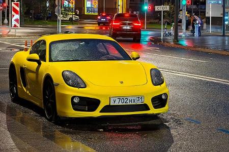 Porsche 718 Cayman in Moskau bei Nacht und Regen