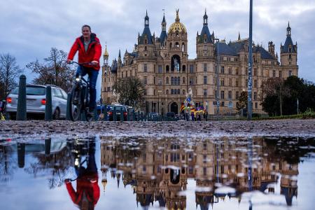 Fahrradfahrer vor dem Schweriner Schloss bei mildem, grauem Wetter in Norddeutschland.