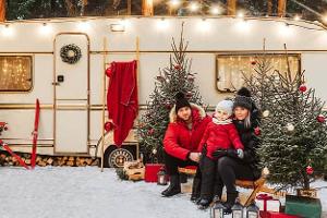Happy family have a good time together near decorated motorhome in winter.