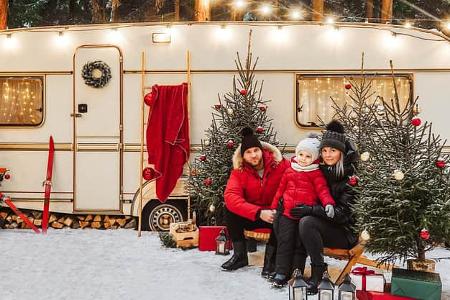 Happy family have a good time together near decorated motorhome in winter.