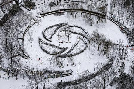 Menschen haben Spaß im Schnee in einem Park in Peking.