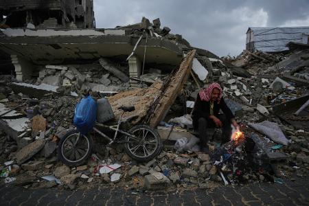 Der Palästinenser Mohammed al-Jabri, 58, wärmt sich neben einem Feuer, während er auf den Trümmern eines Gebäudes sitzt, das während der israelischen Luft- und Bodenoperationen im Viertel Sheikh Radwan zerstört wurden.