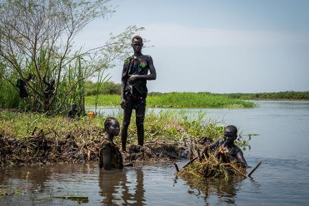 Ayen Deng Duot (r) und ihre Familie befestigen ihre Insel mit Pflanzen und Schlamm aus dem Sumpf, um zu verhindern, dass ihr Haus am Nil überflutet wird.