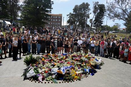Menschen versammelt sich einen Tag nach einer Schießerei am Bondi Beach in Sydney um ein Blumendenkmal.