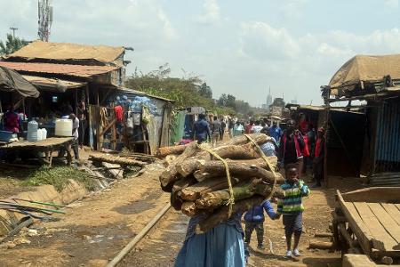Eine Frau trägt ein Bündel Brennholz entlang der Bahnstrecke, die durch Nairobis größten Slum Kibera führt. (Archivbild)