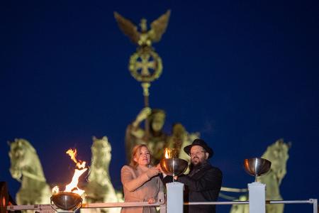Bundestagspräsidentin Julia Klöckner (CDU) und Rabbiner Yehudi Teichtal entzünden am Brandenburger Tor während einer festlichen Zeremonie die Lichter am Chanukka-Leuchter mittels einer Fackel.