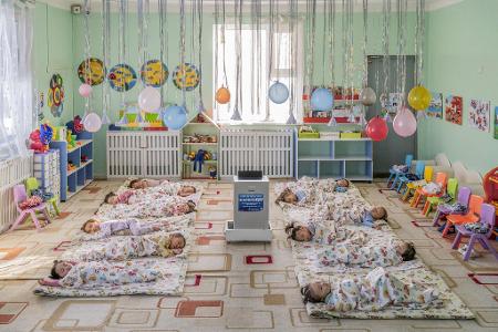 In einem Kindergarten in Ulaanbaatar, der Hauptstadt der Mongolei, liegen Kinder auf dem Boden um einen aufgestellten Luftfilter herum, der die Schadstoffkonzentration senken soll.