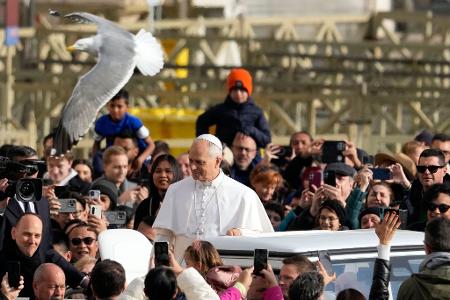 Eine Möwe fliegt vorbei, während der Papst Gläubige auf dem Petersplatz begrüßt.