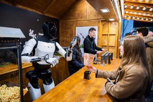 Der humanoide Roboter "Optimus" von Tesla verteilt bei seiner Vorstellung in der Mall of Berlin Popcorn an eine Besucherin.