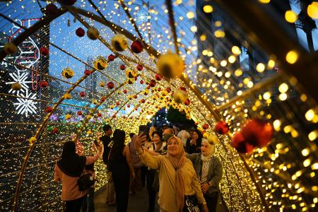 Menschen machen Selfies unter einer Weihnachtsbeleuchtung in Jakarta.