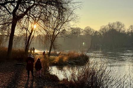 Spaziergänger sind am zugefrorenen Schloßteich in Chemnitz unterwegs.